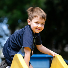 Student climbing on yellow playground equipment outdoors.